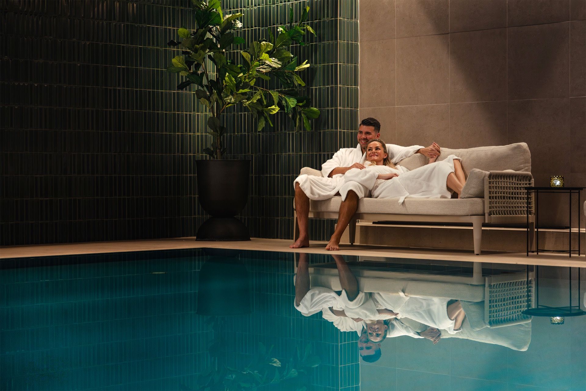 A couple in bathrobes by the indoor pool at St. Elisabeth Suites & Spa, Tromsø